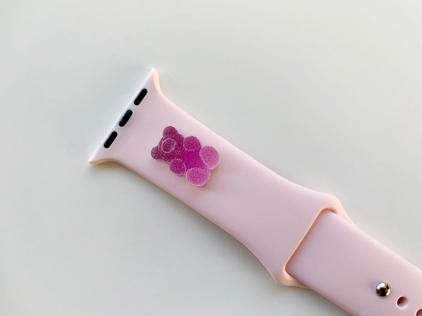 A small purple 3D printed gummy bear attached to a pink silicon watch band for the apple watch