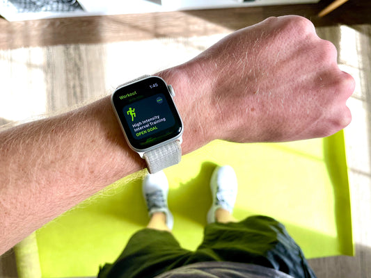 A man looking at his apple watch tracking his fitness at the gym standing on a workout mat