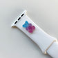 A small blue and purple 3D printed gummy bear attached to a white silicon watch for the apple watch