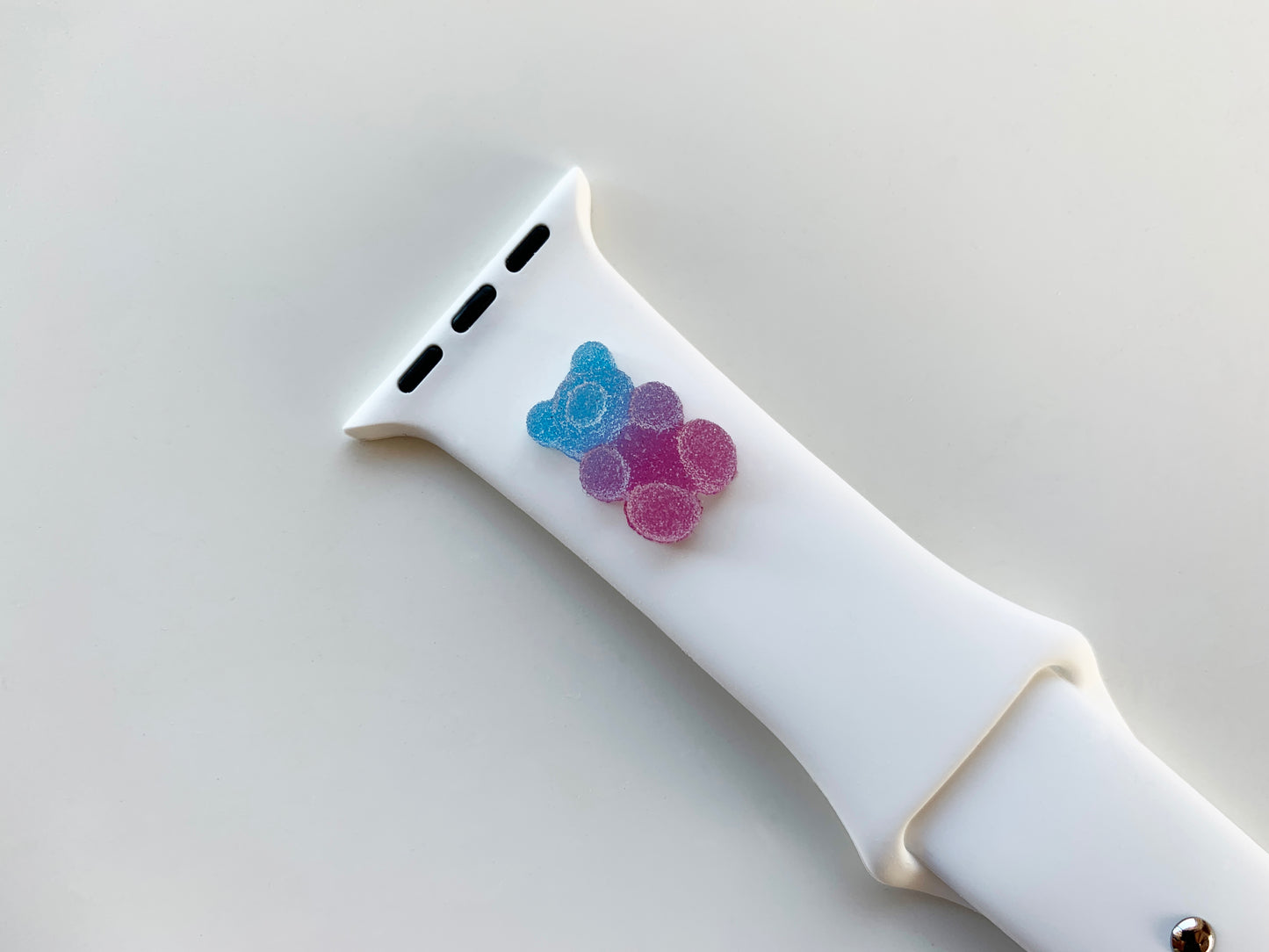 A small blue and purple 3D printed gummy bear attached to a white silicon watch for the apple watch