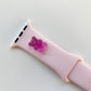 A small purple 3D printed gummy bear attached to a pink silicon watch band for the apple watch